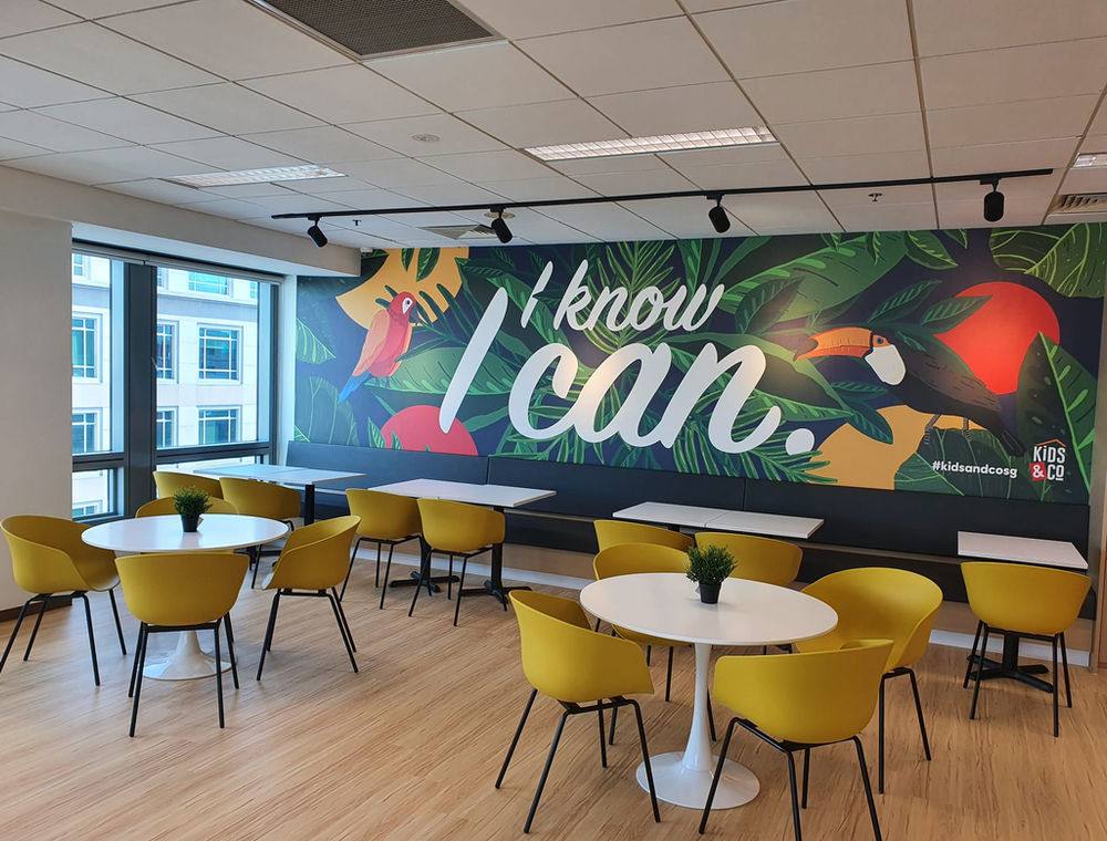 The bright café dining area with yellow chairs and large windows.