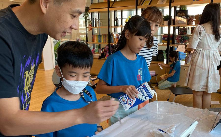 A parent and children doing a hands-on science activity together at a Kids & Co family session.